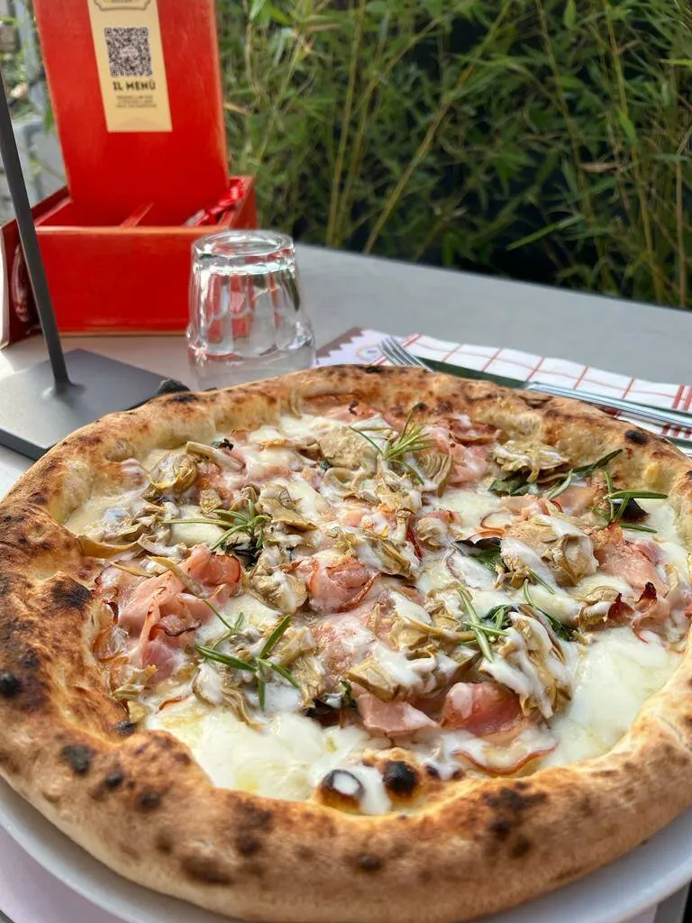 Pizza bianca con funghi e prosciutto servita al tavolo