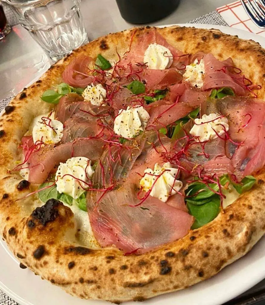 Pizza con carpaccio, stracciatella e germogli dal cornicione alto
