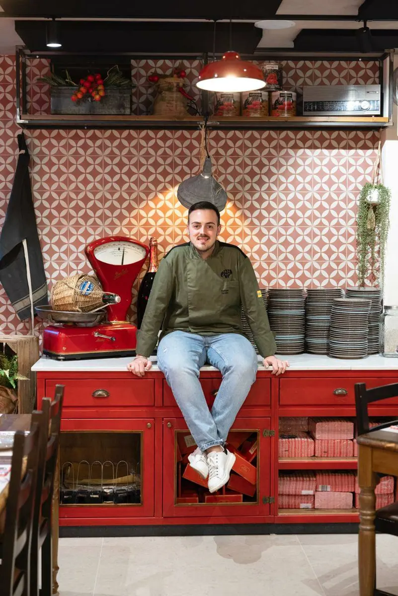 Raffaele Forcella seduto sul bancone rosso della pizzeria