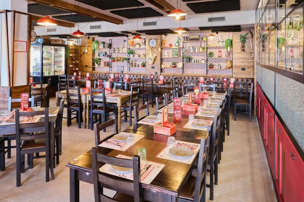 La sala lunga con tavoli apparecchiati e parete decorata